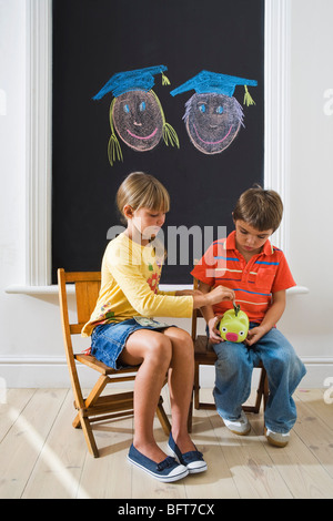 Jungen und Mädchen, Geld im Sparschwein für College Fund Stockfoto