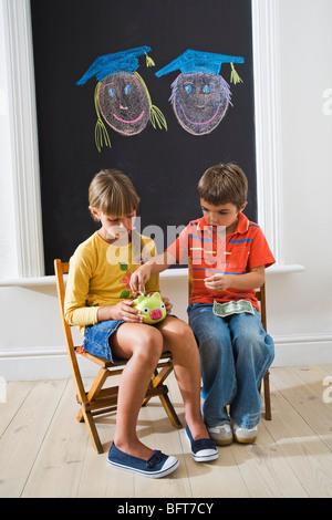 Jungen und Mädchen, Geld im Sparschwein für College Fund Stockfoto