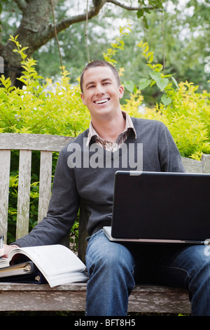 Studenten sitzen auf einer Bank mit einem Laptopcomputer Stockfoto