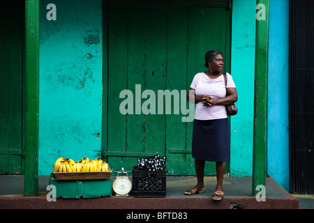 Schwarze Frau Verkauf von Bananen aus einem Korb auf der Straße, St. Johns, Antigua Stockfoto