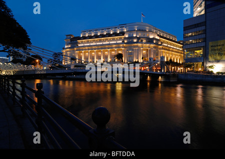 Das luxuriöse, gehobene Fullerton Hotel (das ehemalige zentrale Postamt) beleuchtet bei Nacht und der Singapore River, Singapur Stockfoto