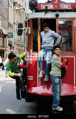 Jungs hängen von der Rückseite der Straßenbahn auf der Istiklal Caddesi in Istanbul Stockfoto
