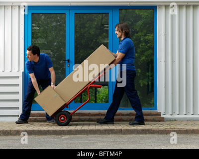 zwei Männer tragen Kisten auf Wagen Stockfoto