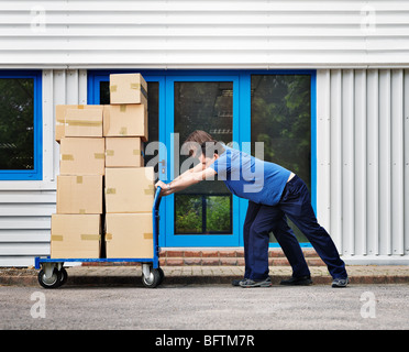 zwei Männer, die Umzugskartons auf Wagen Stockfoto