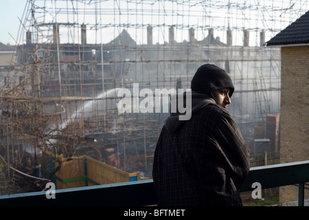 Jungen Hoodie sieht die Verwüstung einer Baustelle nach einem innerstädtischen Immobilien Brand in Südlondon. Stockfoto