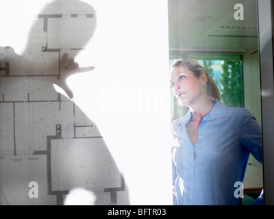 Mann und Frau hinter Blaupausen Stockfoto