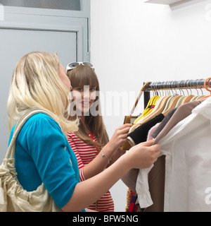 2 junge Frauen stehen auf Kleiderstange Stockfoto