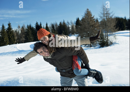 Junge Frau Reiten Huckepack auf jungen Mann im Winter-Szene Stockfoto