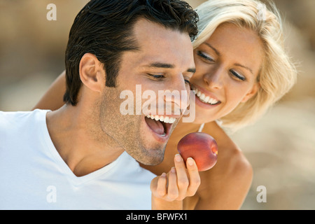 Ein Weibchen füttern einem Latein-Mann einen Apfel. Stockfoto