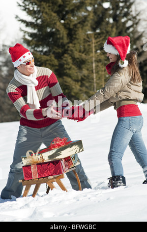 Paar im Weihnachts-Outfit, hält ein Geschenk Stockfoto