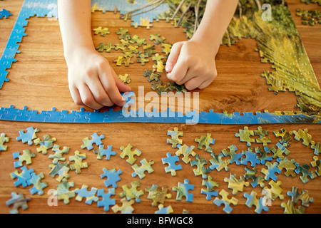 Einige Hände arbeiten auf ein puzzle Stockfoto