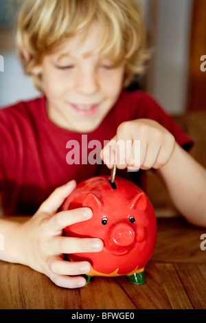 Ein Junge, Geld in ein Sparschwein Stockfoto