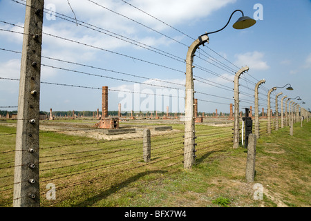 Umzäunung / Nazi-Vernichtungslager Birkenau (Auschwitz II-Birkenau) in Oswiecim, Polen & gemauerte Schornsteine aus Etagenbett Häuser hinter Stockfoto