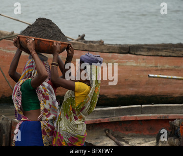 Weibliche Arbeitnehmer tragen jede Menge Sand und Splitt aus Bergbau-Boote auf dem Fluss Tapei im nördlichen indischen. Stockfoto