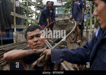 Männer biegen Eisenstangen für den Transport per Boot am Steg Yangon in Myanmar, Burma Stockfoto