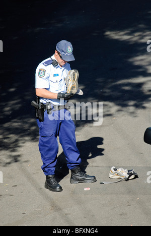 Polizisten untersuchen die Schuhe und Gürtel eines Mannes hat er nur verhaftet. Sydney, New South Wales, Australien. Stockfoto