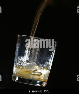 Whisky in ein Glas mit Eiswürfel gegossen wird Stockfoto