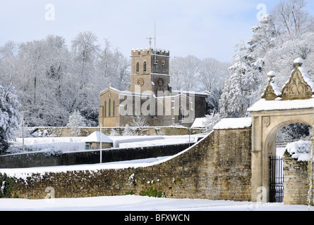 Oxfordshire Kirche in Sonnenschein und frisch gefallenem Schnee mit einem sanften blauen Himmel dahinter. Tor vor.  Schneebedeckte Bäume. Stockfoto