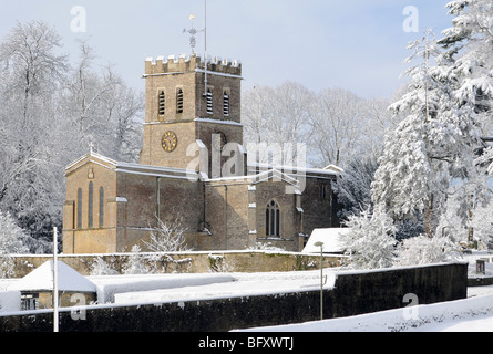 Oxfordshire Kirche in Sonnenschein und frisch gefallenem Schnee mit einem sanften blauen Himmel dahinter.  Felder im Vordergrund. Stockfoto