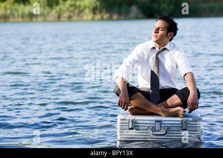 Geschäftsmann, sitzen auf schwimmenden Koffer Stockfoto