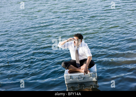 Geschäftsmann, sitzen auf schwimmenden Koffer Stockfoto