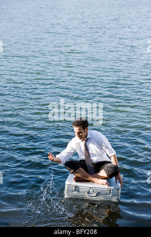 Geschäftsmann, sitzen auf schwimmenden Koffer Stockfoto