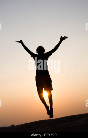 Silhouette eines indischen Jungen, der bei Sonnenuntergang in die Luft springen. Indien Stockfoto