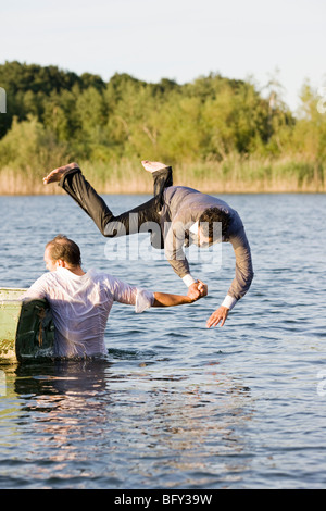 Geschäftsmann werfen Freund im Wasser Stockfoto