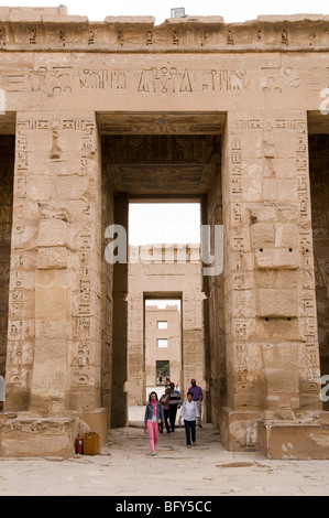 Touristen gehen durch ein Tor oder Pylon in das Mittelschiff im Inneren Tempel der Habu Medenet in der Nähe von Luxor Ägypten. Stockfoto