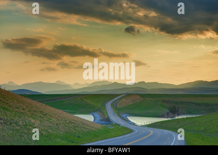 Autobahn-Abfahrten durch Prairie Coulee und in Entfernung in Richtung Rocky Mountains, Alberta, Kanada Stockfoto