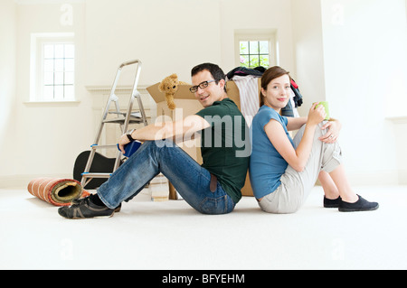 Ein junges Paar Rücken an Rücken sitzen. Stockfoto