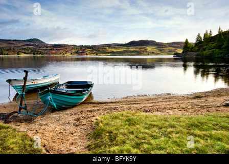 Die entfernten Loch Ordie, nr Dunkeld, Schottland, aufgenommen kurz nach Sonnenaufgang mit zwei alten Ruderboote im Vordergrund Stockfoto