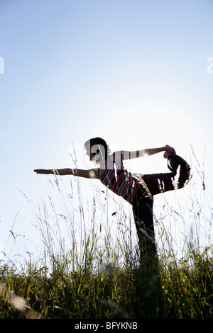 Frau Durchführung Yoga In Wiese Stockfoto