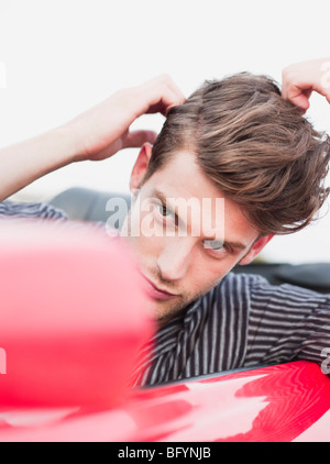 Mann sucht in Außenspiegel des Autos Stockfoto