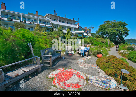 Paar genießt den Garten und die Aussicht auf das Wasser und die Berge vom Garten zur Luxusherberge auf Vancouver Island, Kanada. Stockfoto