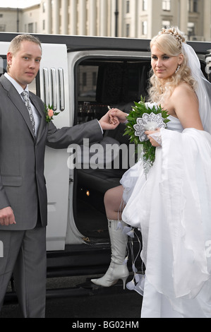 Bräutigam trägt Braut im Auto sitzen. Junges Paar kaukasischen. Stockfoto