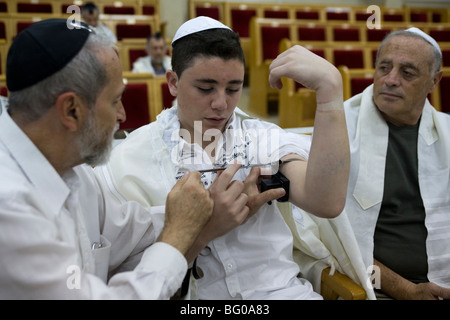 Bar Mizwa Junge Verlegung Tefillin (Gebetsriemen) während der Zeremonie Stockfoto