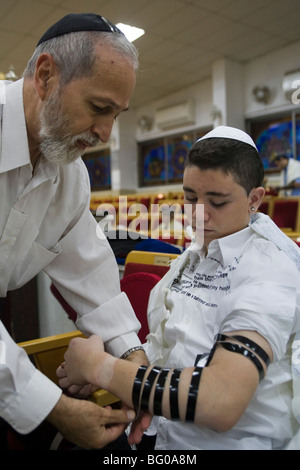 Bar Mizwa Junge Verlegung Tefillin (Gebetsriemen) während der Zeremonie Stockfoto