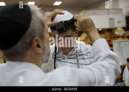 Bar Mizwa Junge Verlegung Tefillin (Gebetsriemen) während der Zeremonie Stockfoto