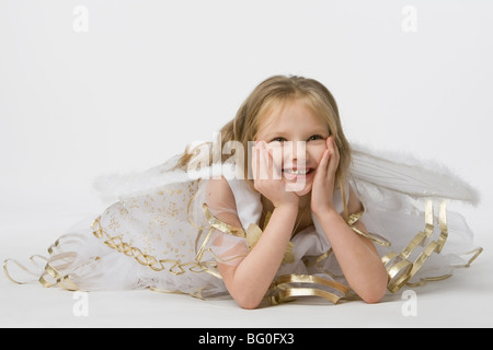 wunderschönes kleines Mädchen im Anzug Schmetterling mit Flügeln hält Palmen über Person und liegen am Boden Stockfoto