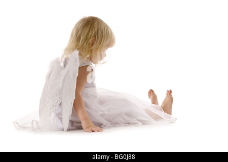 kleines Mädchen im weißen Kleid und Engel Flügel auf dem Rücken, isoliert auf weiss leider sitzen Stockfoto