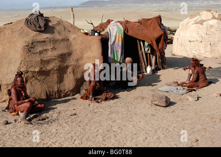 Mitglieder des Stammes Himba entspannend vor ihren Behausungen, Kaokoland, Namibia, Afrika Stockfoto