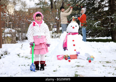 Familie neben Schneemann Stockfoto