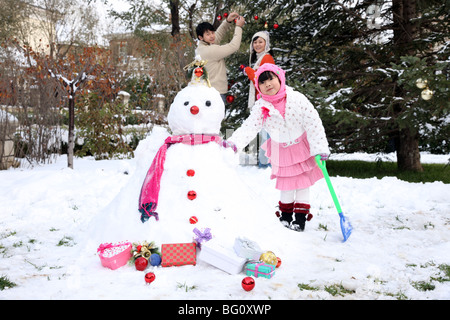 Familie neben Schneemann Stockfoto