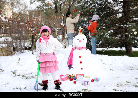 Familie neben Schneemann Stockfoto