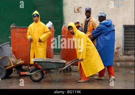 Arabischen und afrikanischen Arbeiter des öffentlichen Reinigungs Service in gelb und blau Regenmäntel, Tripolis, Libyen Stockfoto