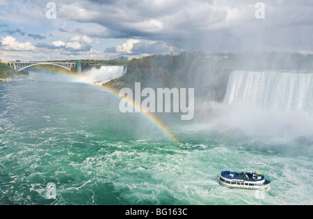 Mädchen der Nebel Tour Ausflug Boot unter den Horseshoe Falls Wasserfall mit Regenbogen am Niagara Falls, Ontario, Kanada Stockfoto