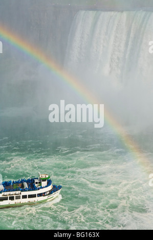 Mädchen der Nebel Tour Ausflug Boot unter den Horseshoe Falls Wasserfall mit Regenbogen am Niagara Falls, Ontario, Kanada Stockfoto
