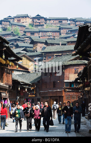 Touristen zu Fuß von Holzhäusern auf den alten Straßen von Xijiang, Provinz Guizhou, China, Asien Stockfoto