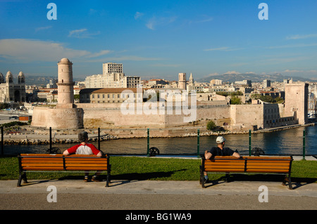 Besucher oder Touristen auf Parkbänken bewundern den Blick über Fort Saint Jean & Vieux Port vom Park Palais du Pharo, Marseille oder Marseille, Frankreich Stockfoto